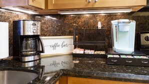 Una cocina con cafetera, dispensador de agua y letrero de barra de café.