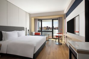 Une chambre d’hôtel avec un grand lit, une table à manger, un téléviseur et une vue sur la ville.