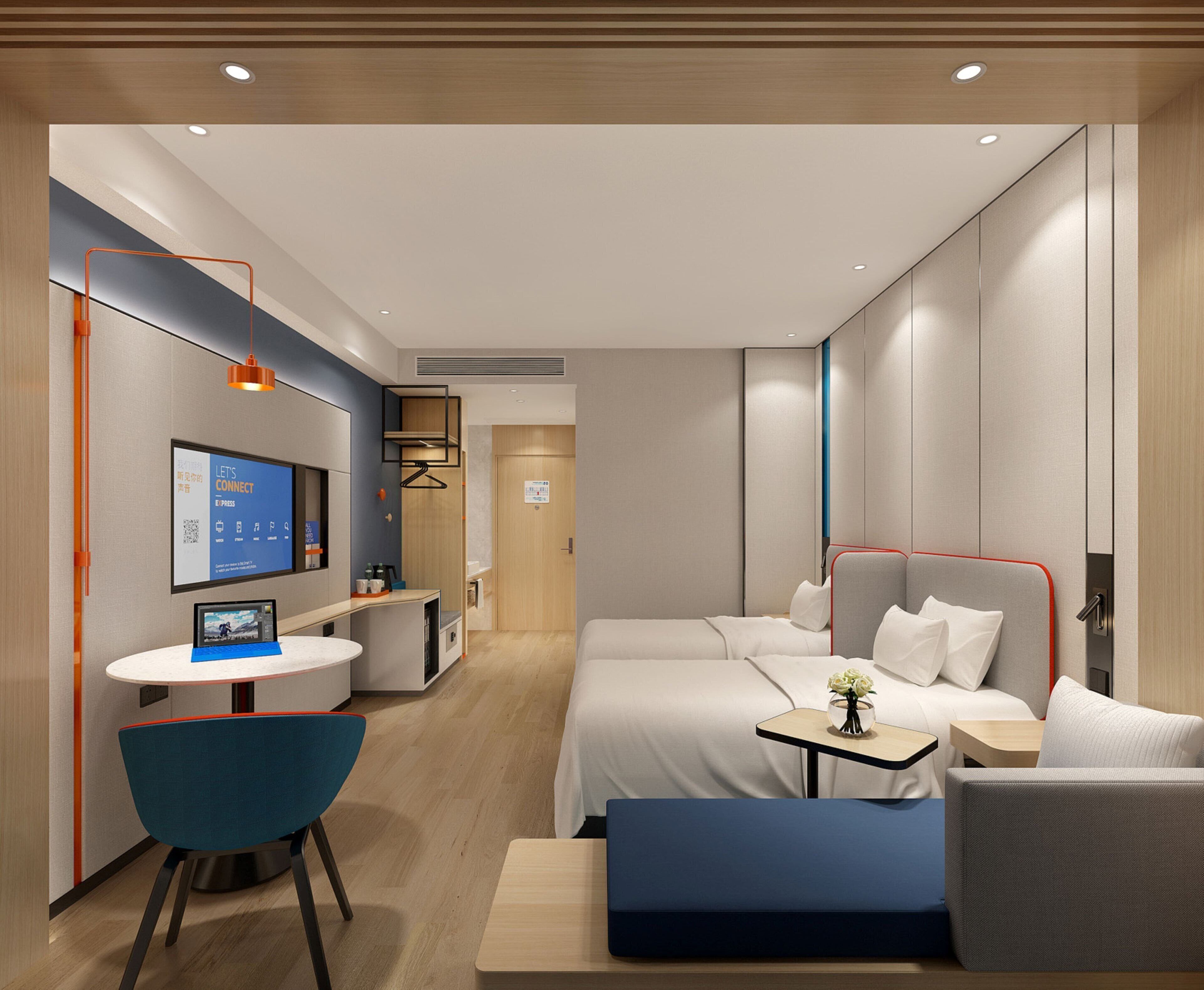Une chambre d’hôtel moderne équipée d’un lit, de tables de chevet, d’un bureau avec une chaise et d’un téléviseur.