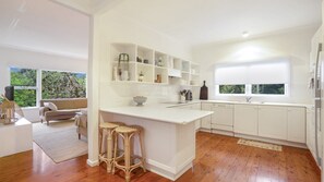 A modern kitchen with white cabinetry, a central island, and a view of greenery outside.