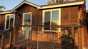 A house with a wooden exterior, a brick chimney, and a balcony with metal chairs.