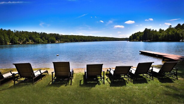 Vista al lago con un muelle y sillones de descanso orientados al agua.