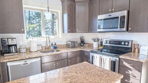 Una cocina moderna con encimeras de granito, electrodomésticos de acero inoxidable y armarios de madera oscura.