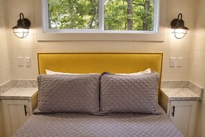 Een bed met een gewatteerd hoofdbord, twee nachtkastjes en wandlampen.
