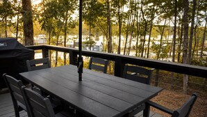 Una terraza con mesa y sillas, con vistas a un área boscosa y un cuerpo de agua.