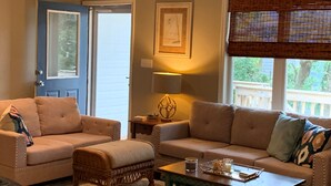 A living room with two sofas, a coffee table, and a door with a window. - Private, Spacious Beach Retreat with Fenced in Shaded Yard (Kill Devil Hills)