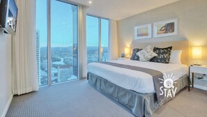 Habitación de hotel con una cama grande, una televisión de pantalla plana, vistas a la ciudad y dos cuadros en la pared.