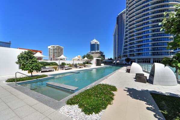Relax by the pool surrounded by lush gardens and shaded lounge chairs.