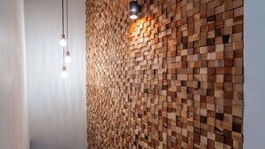 Pared con diseño de bloques de madera, dos lámparas colgantes y una lámpara de techo.
