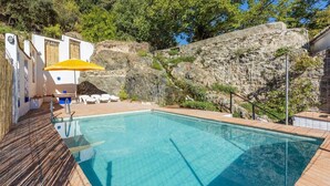 En pool med træterrasse, hvide liggestole og en gul parasol.