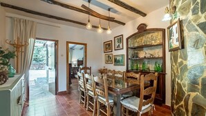Uma área de refeições com mesa e cadeiras de madeira, parede de pedra e um espelho.