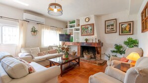 Uma sala de estar aconchegante com lareira, assentos confortáveis e objetos decorativos.