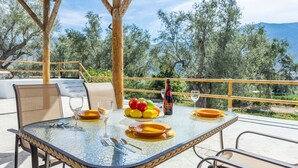 An outdoor dining area with a round glass table, chairs, and a view of trees and mountains. - Cortijo Villa Maroma Órgiva by Ruralidays (Granada)