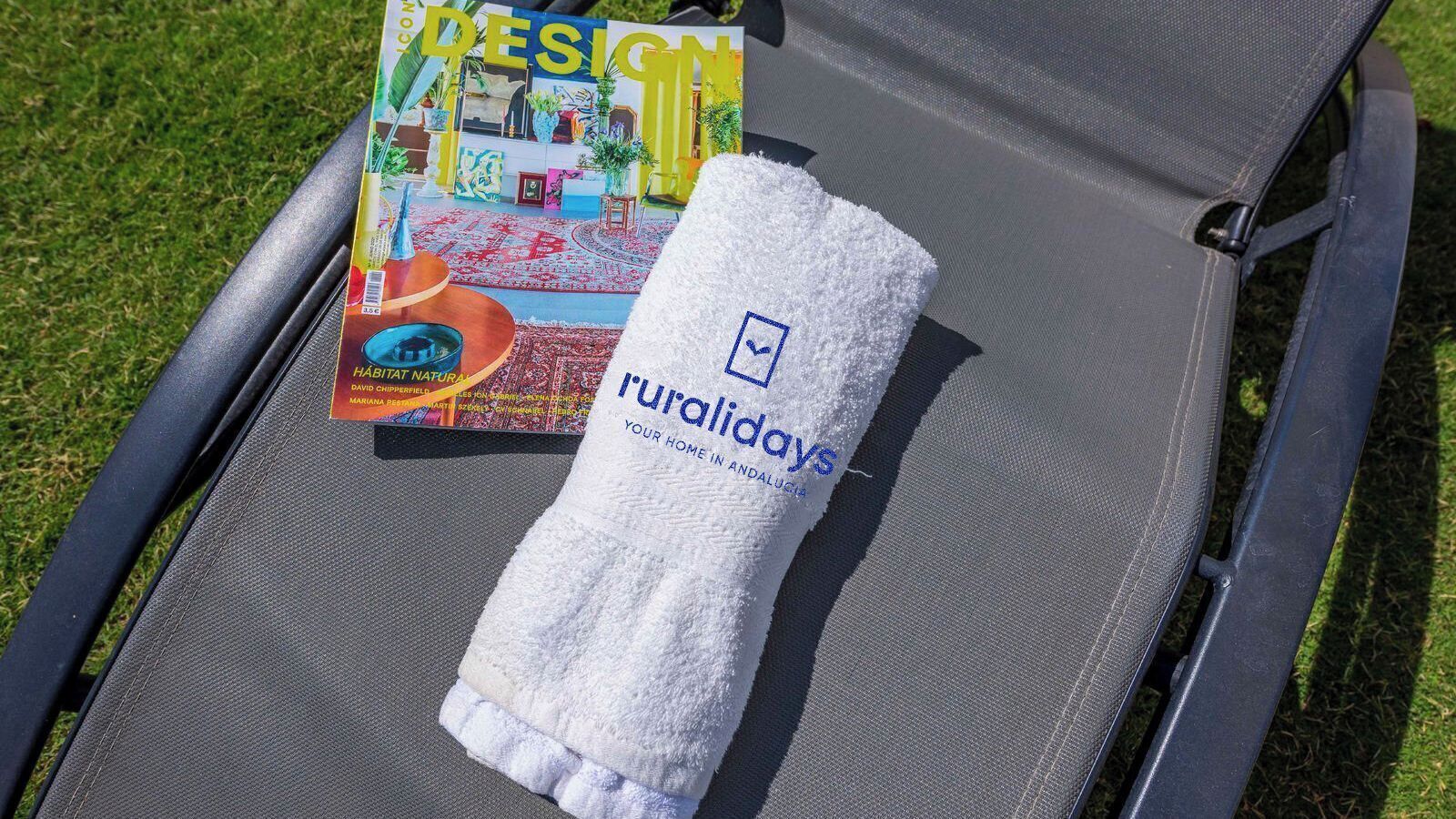 A lounge chair with a towel and a magazine on it.