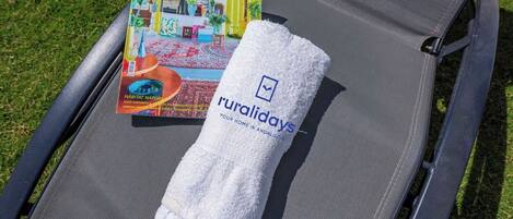 A lounge chair with a towel and a magazine on it.