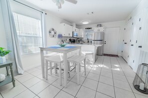 A modern kitchen with white cabinetry, a dining table with chairs, and a large island.