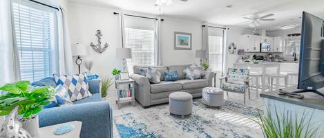 A modern living room with a grey sofa, blue and white patterned cushions, a coffee table, and a blue and white patterned rug.