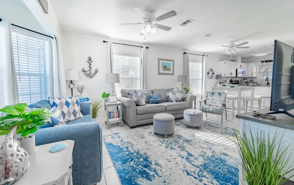 A modern living room with a grey sofa, blue and white patterned cushions, a coffee table, and a blue and white patterned rug.