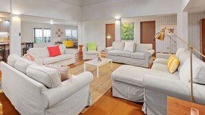 Un salon spacieux avec plusieurs coins salon, une table basse et une lampe.