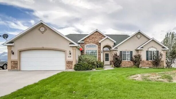A two-story house with a garage, a stone facade, and a well-maintained lawn.