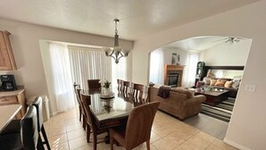 A spacious living area with a dining table and chairs, a sofa, and a fireplace.