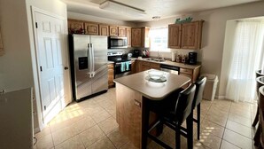 A kitchen with wooden cabinets, a stainless steel refrigerator, a microwave, and a coffee maker.