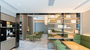 A modern library with bookshelves, seating areas, and a coffee machine. - Ji Hotel Shanghai Xinzhuang (Shanghai)