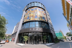 A modern hotel with a curved facade, large glass windows, and a prominent entrance with a revolving door.