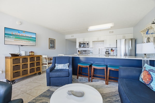 A modern living room with a sofa, a coffee table, and a TV displaying a vacation ad.