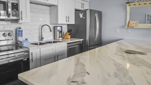 Una cocina moderna con armarios blancos, electrodomésticos de acero inoxidable y encimera de mármol.