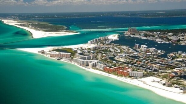 An aerial view of a coastal resort with beachfront properties, clear turquoise waters, and a marina. - Island Surf #8  1st Floor + Poolside + Beachfront + Beach Service! (Fort Walton Beach)