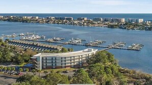 Uma marina com barcos, um edifício moderno e um horizonte costeiro.