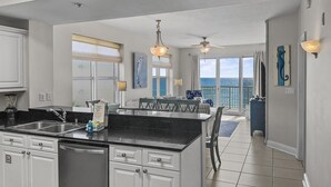 Una cocina moderna con una isla grande, armarios blancos y vistas al océano.