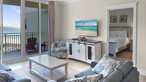 Una habitación con sofá, mesa de centro, armario, cama y vistas a la playa.