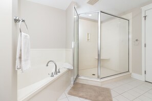 Une salle de bain moderne avec une douche à parois de verre, une baignoire et une serviette blanche suspendue à un anneau métallique.