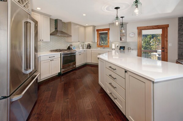 A modern kitchen with white cabinetry, a stainless steel refrigerator, and a large island. - Modern Sophisticated Chic, Walk to Slopes, Waterfront condo In the heart of Keystone (Keystone)