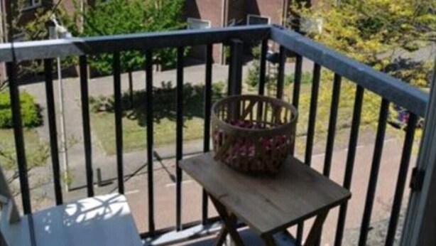 Een balkon met een houten stoel en een rieten mand.