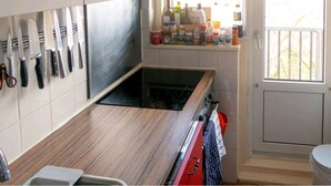 Een keuken met een houten aanrecht, een ingebouwde kookplaat en een raam met uitzicht op gebouwen.