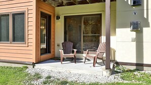Une maison avec un porche, deux fauteuils Adirondack, une porte-fenêtre coulissante et un thermostat réglé sur la température la plus élevée.