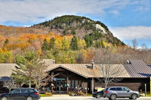 Un chalet avec une façade en bois, une véranda et une vue sur les montagnes en arrière-plan.