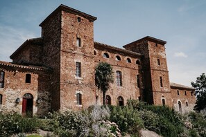 Experience the grandeur of this historic building, featuring a symmetrical facade with arched windows and a central tower, set amidst a serene garden.