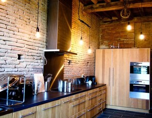 Enjoy cooking in this kitchen with exposed brick walls, wooden cabinetry, and stainless steel appliances.