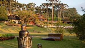 A rustic cabin with a wooden deck and a staircase leading to a second level. - Surya Pan Hotel e Eventos (Campos do Jordão)
