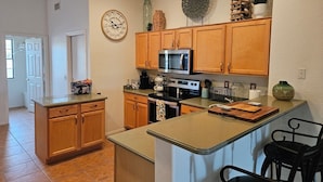 A modern kitchen with wooden cabinets, a central island, and a microwave. - 5 STAR Goodyear Spring Training Hiking Mountain Views Heated Pool Included (Goodyear)