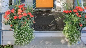 A house with a number 1535 on the front, a wooden door, and two flower planters with red flowers. - Palmer House, Studio 4, Cozy Downtown Studio for 2, Local Golfing 50% Off! (Baker City)