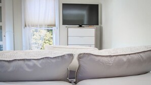 A bedroom with a bed, a television on a stand, and a window with curtains. - Palmer House, Studio 4, Cozy Downtown Studio for 2, Local Golfing 50% Off! (Baker City)