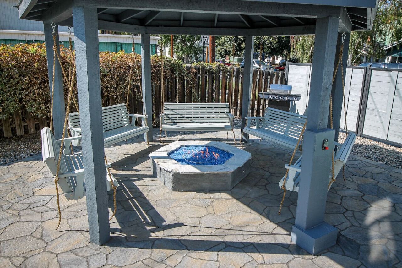 A covered outdoor seating area with benches and a fire pit.