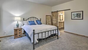 Een slaapkamer met een bed, nachtkastje, lamp, plafondventilator en een deur naar een andere kamer.
