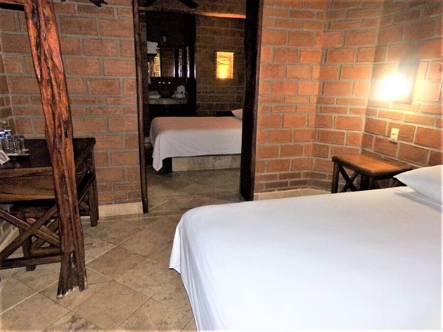 A room with two beds, a wooden table, and a brick wall.