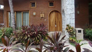 Una casa de maó amb una porta de fusta, una finestra petita i un pilaret de pedra.